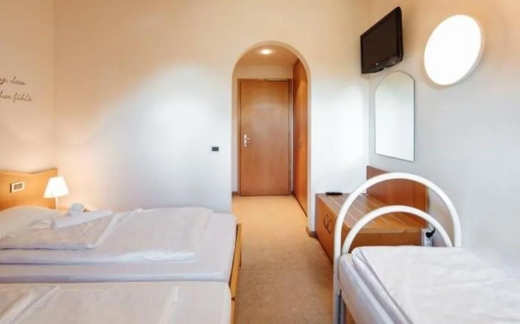 Camera con letti e televisore a parete vicino all'ingresso ad arco